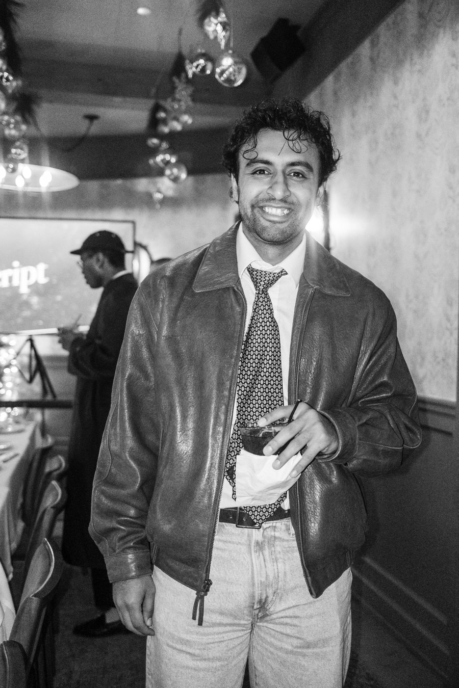 guest in a leather jacket and patterned tie holding a drink