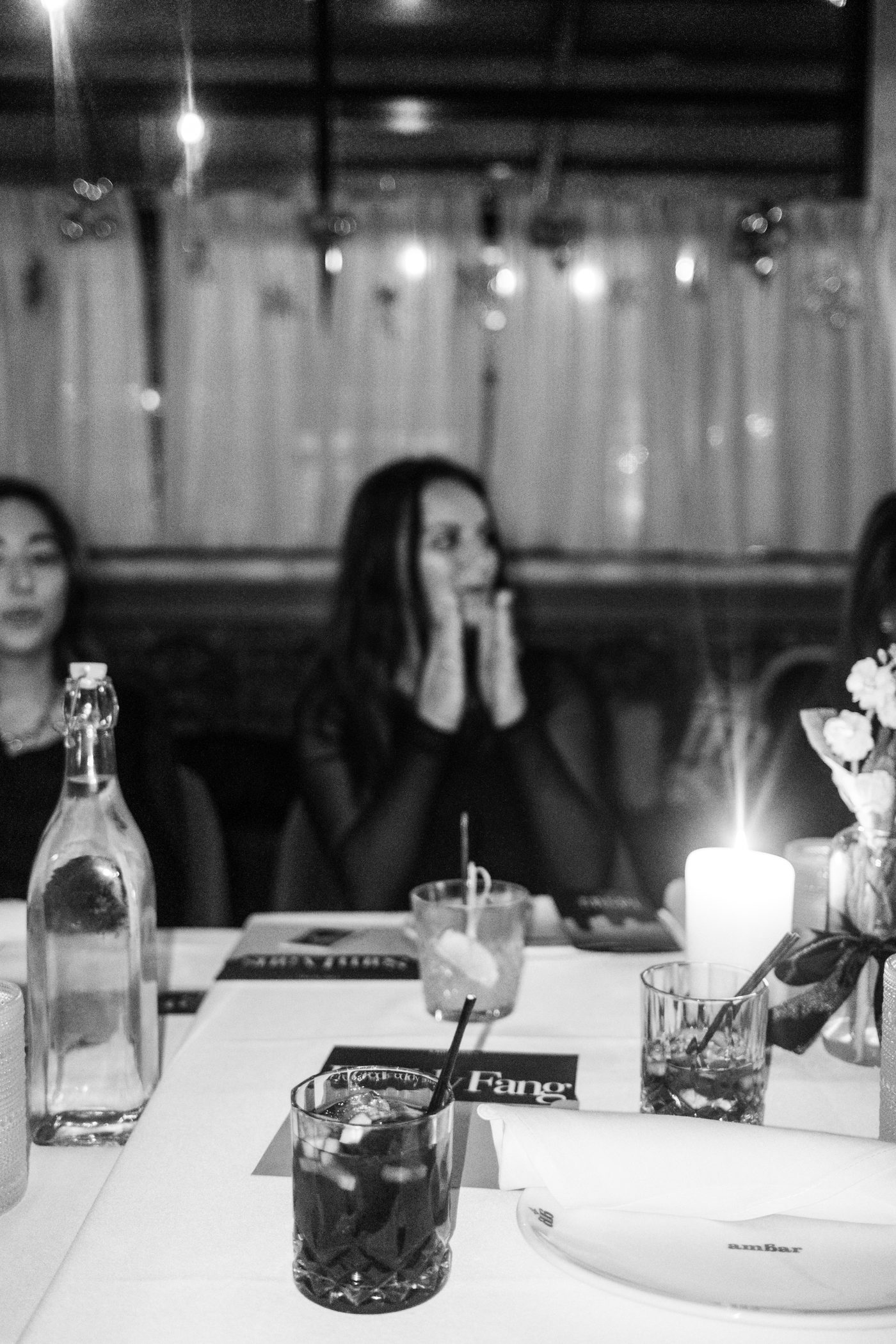 a name card reading fang beside cocktails and a candle