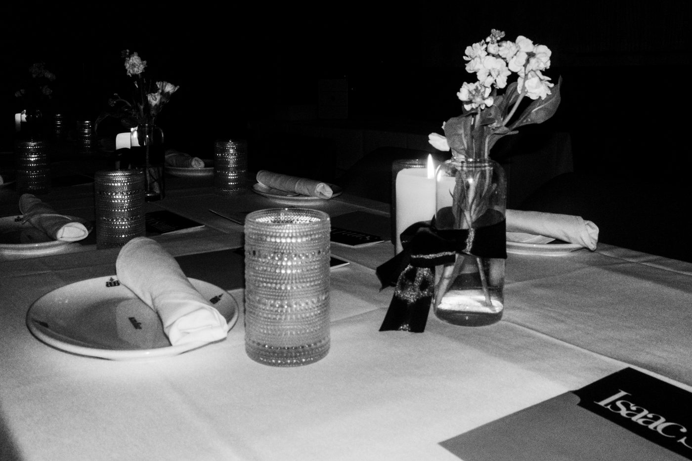 a place setting with a name card, rolled napkin and flowers