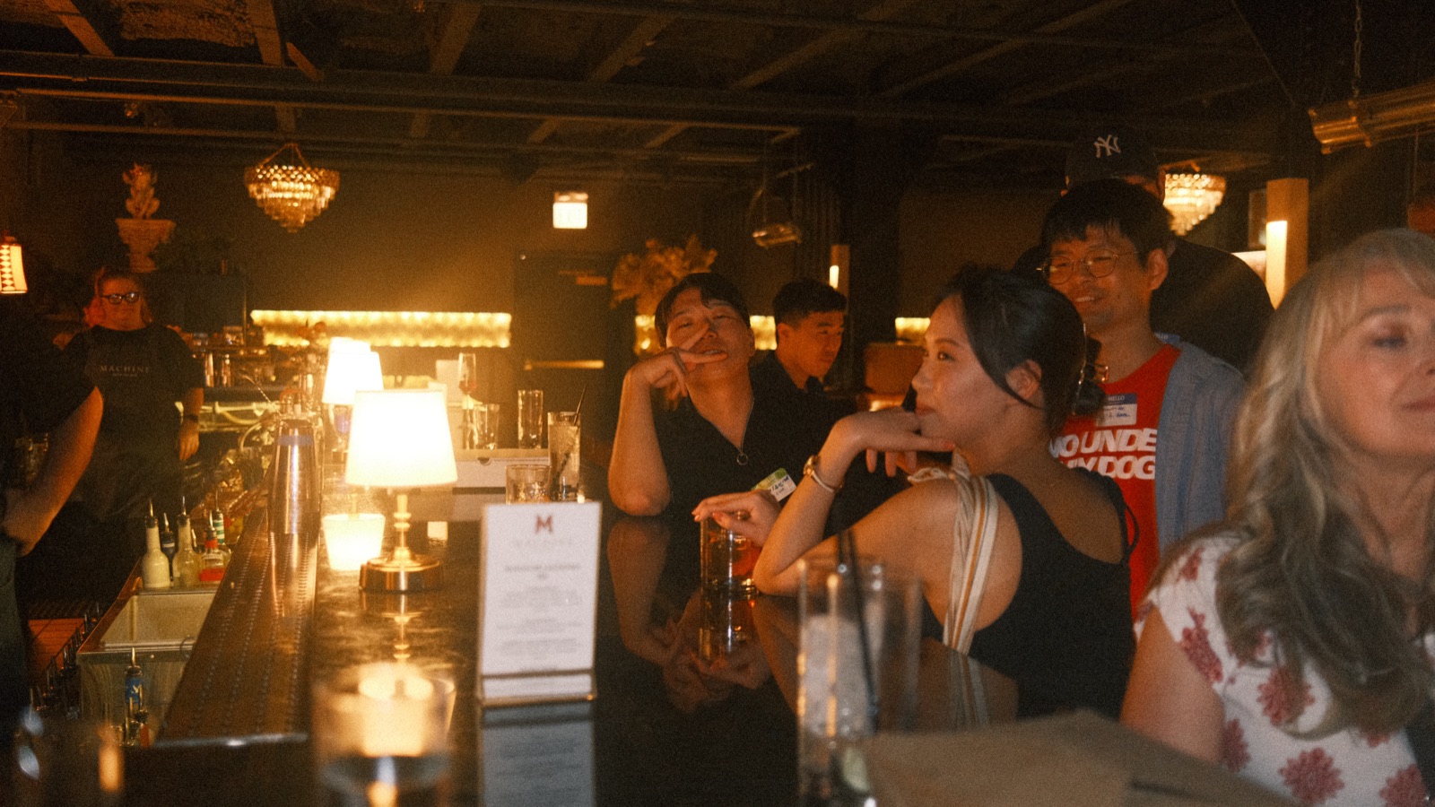the lamp-lit bar at vol 2, guests leaning in with drinks