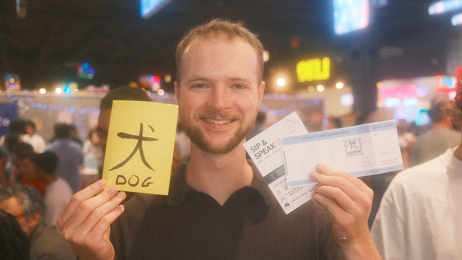 a guest holding up the 犬 dog flashcard and his stamped sip & speak passport